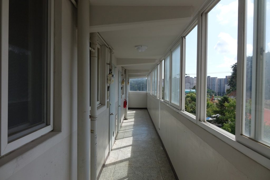 한쪽에 세대 현관, 다른 쪽에 창이 길게 이어진 한국 복도식 아파트의 공용 복도