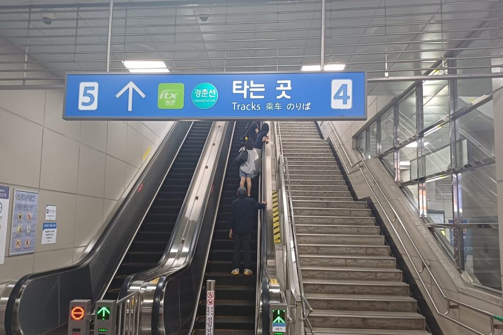 서울 상봉역 경춘선 타는 곳으로 올라가는 에스컬레이터에 승객들이 서서 올라가고 바로 옆에 계단이 있는 모습