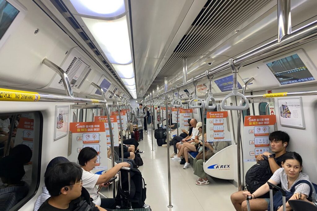 승객 몇 명이 앉아 있고 통로가 비어 있는 비교적 한산한 서울 지하철 객실